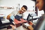 Customer choosing steak at a retail meat counter